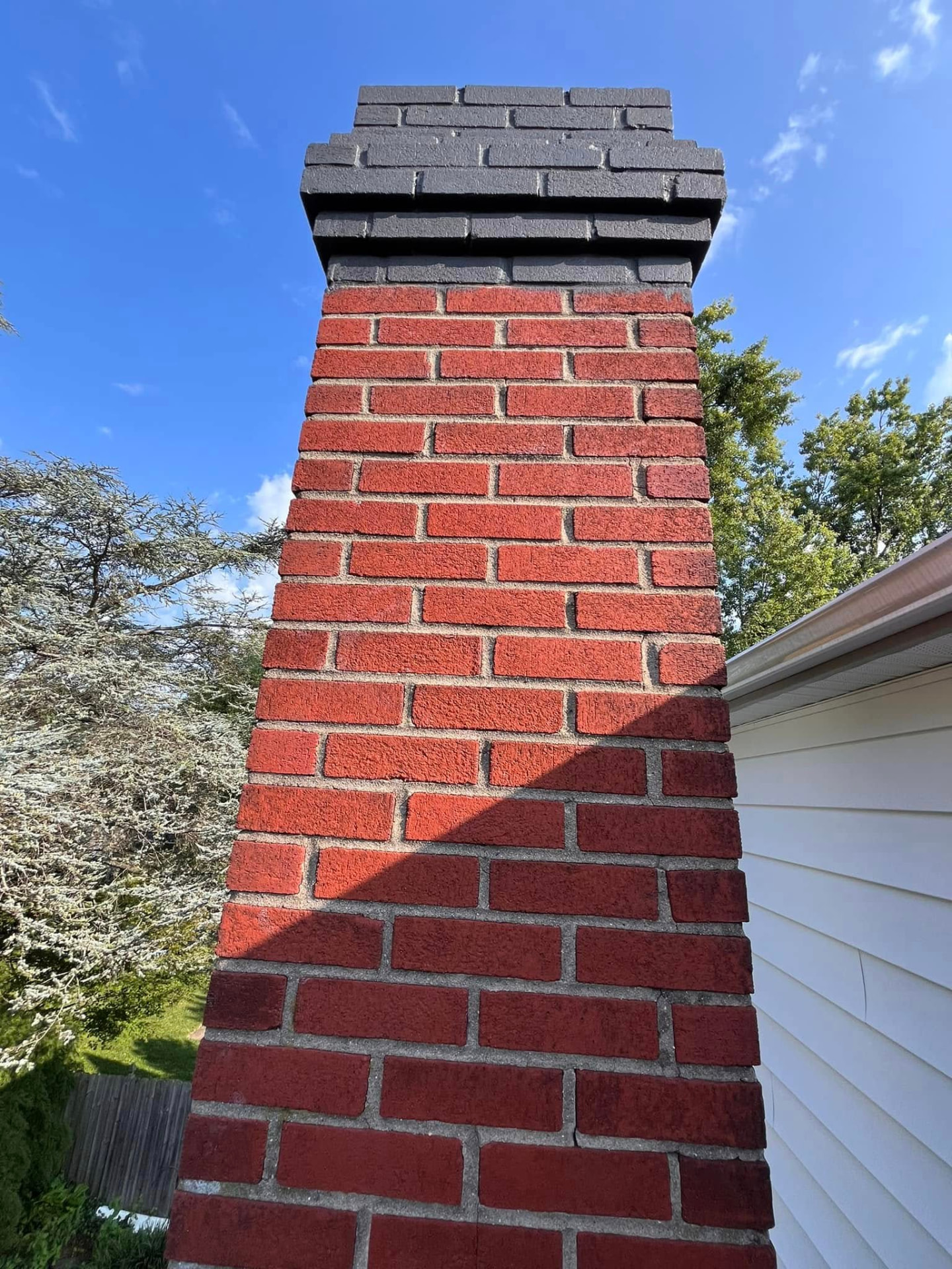 Red brick chimney with a painted grey crown before refinishing