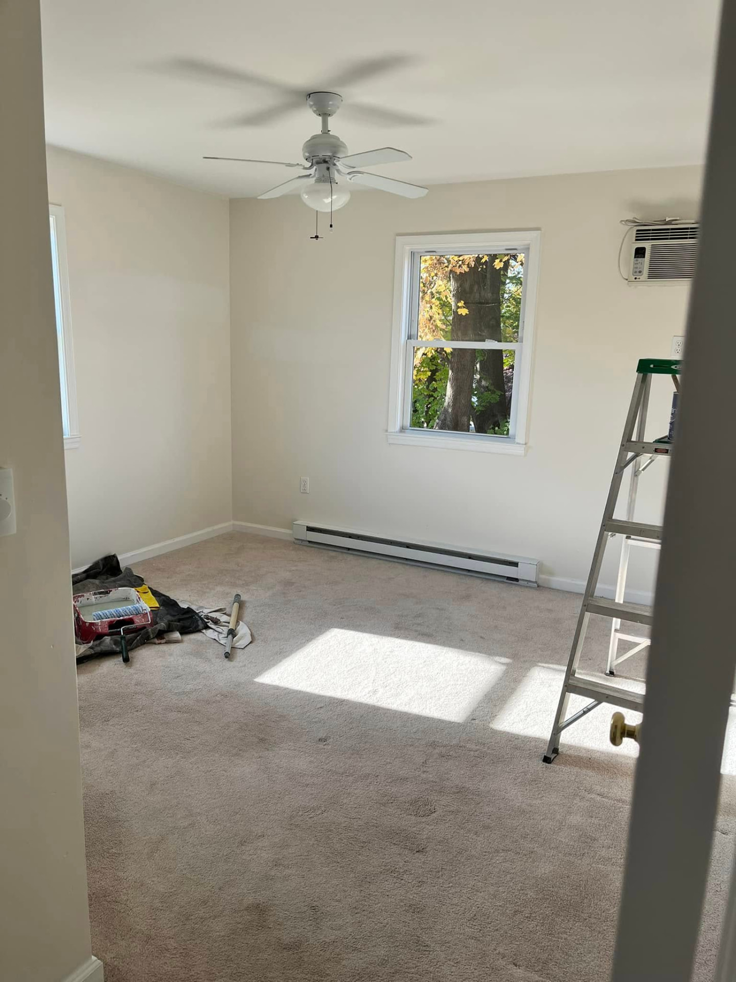 Bedroom before painting with plain off-white walls and drop cloths on the floor